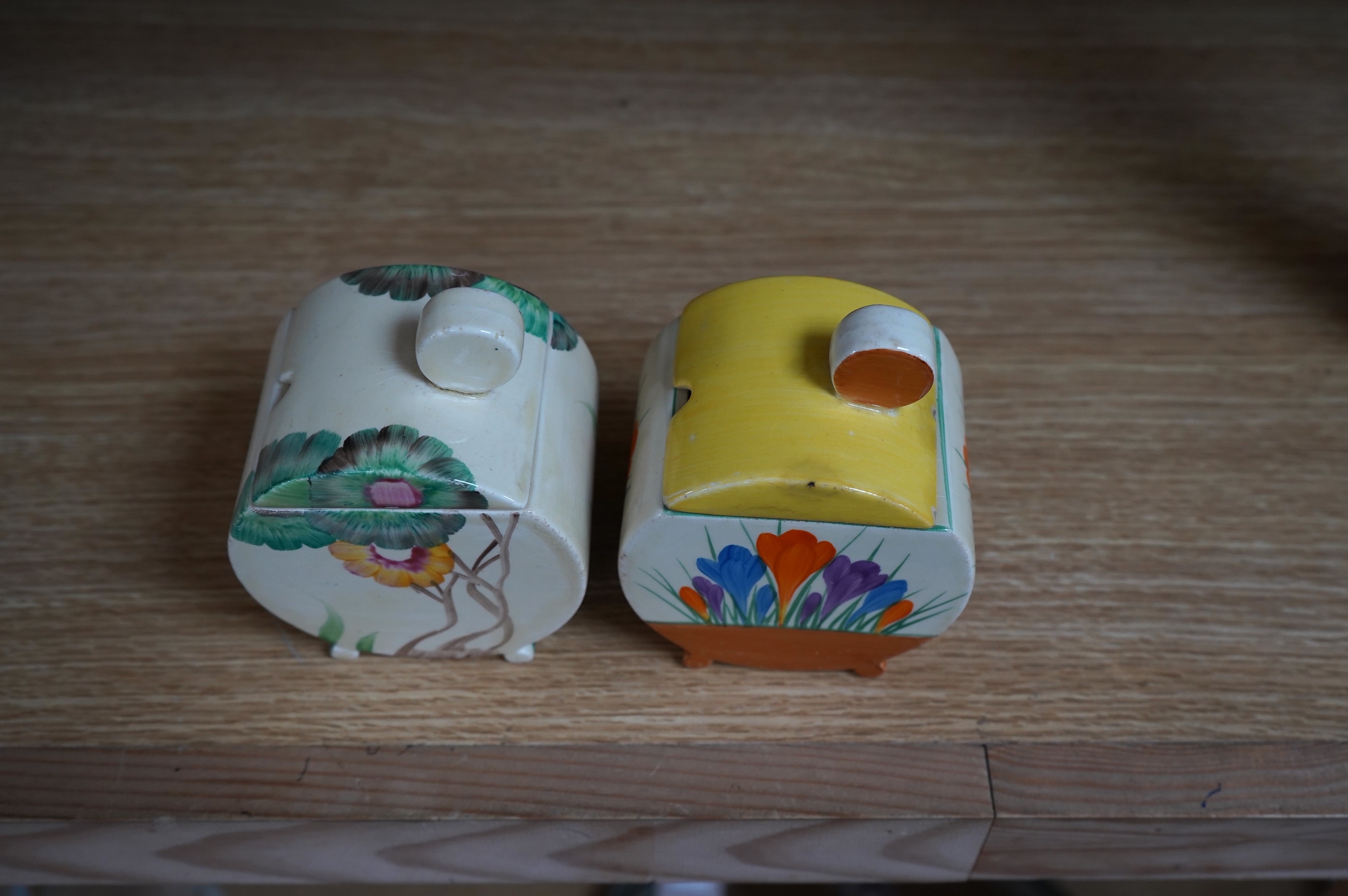 Two Clarice Cliff drum shaped preserve pots and covers, one in Crocus pattern and the other in Viscaria pattern. Condition - good
